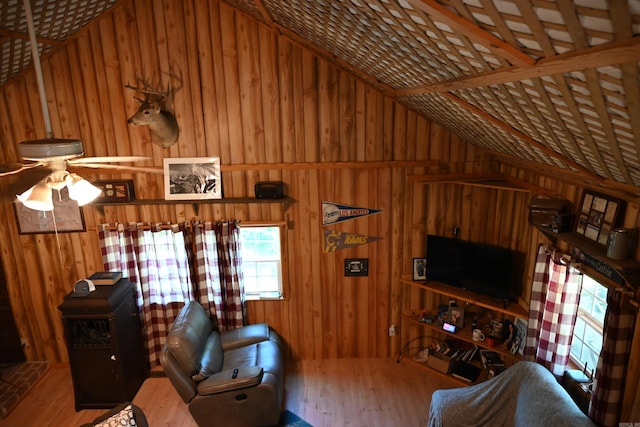 living room with hardwood / wood-style flooring, vaulted ceiling, wood walls, and ceiling fan