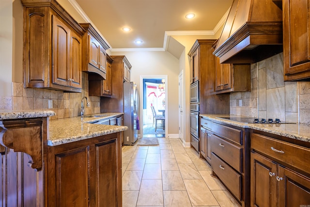 kitchen featuring backsplash, sink, custom range hood, appliances with stainless steel finishes, and light stone counters