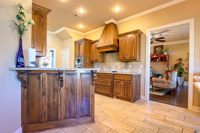 kitchen featuring backsplash, stainless steel microwave, light wood-type flooring, custom exhaust hood, and ceiling fan