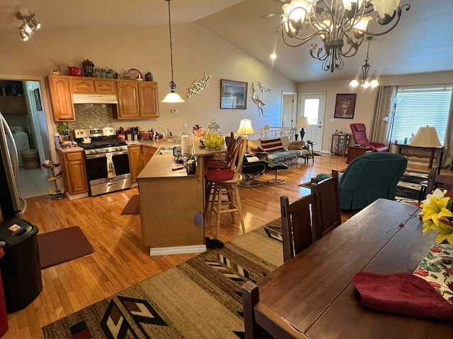 dining space featuring sink, high vaulted ceiling, a chandelier, and light wood-type flooring