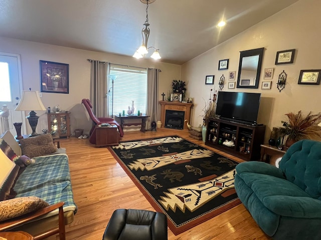 living room featuring a notable chandelier, light hardwood / wood-style floors, and lofted ceiling