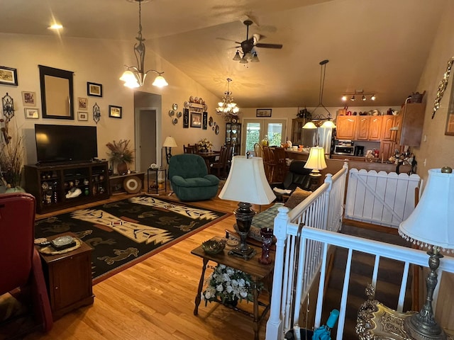 living room with rail lighting, light hardwood / wood-style flooring, ceiling fan with notable chandelier, and lofted ceiling