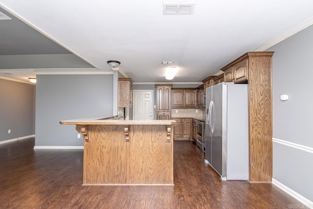 kitchen featuring a breakfast bar, crown molding, appliances with stainless steel finishes, and dark hardwood / wood-style floors