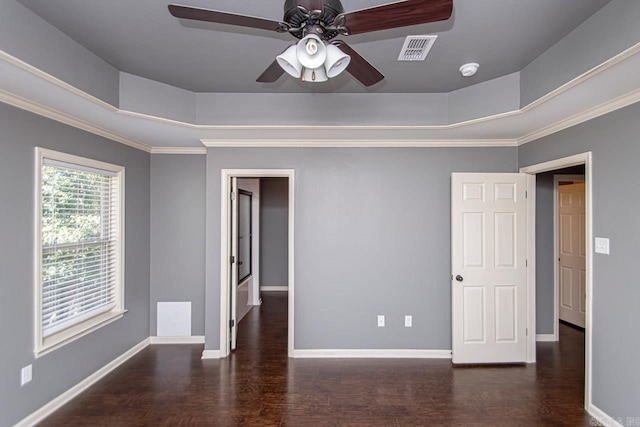 unfurnished room featuring ceiling fan, a raised ceiling, dark hardwood / wood-style floors, and crown molding