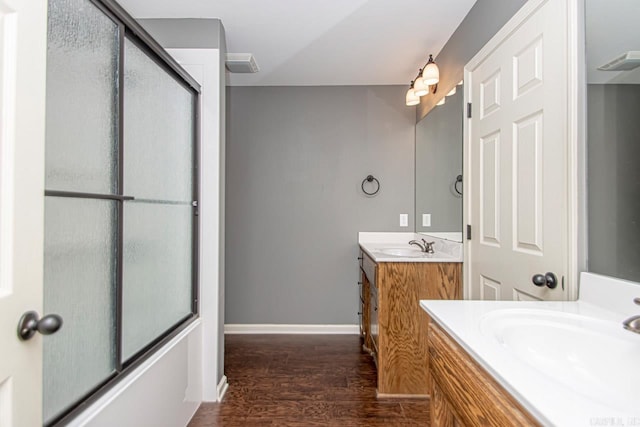 bathroom featuring hardwood / wood-style flooring, vanity, and combined bath / shower with glass door