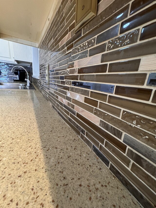 interior details with sink, light stone counters, and white cabinets