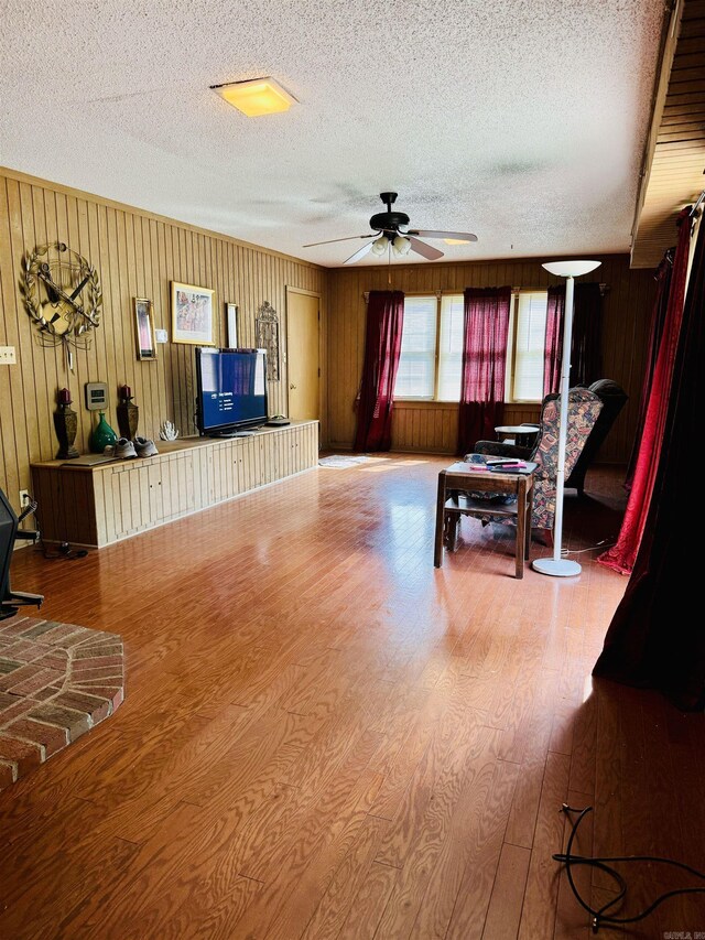 living room featuring hardwood / wood-style floors, a textured ceiling, and wood walls