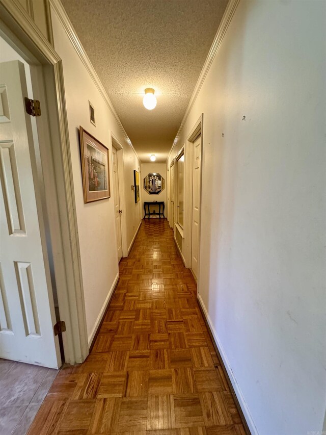 corridor featuring a textured ceiling, ornamental molding, and dark parquet flooring