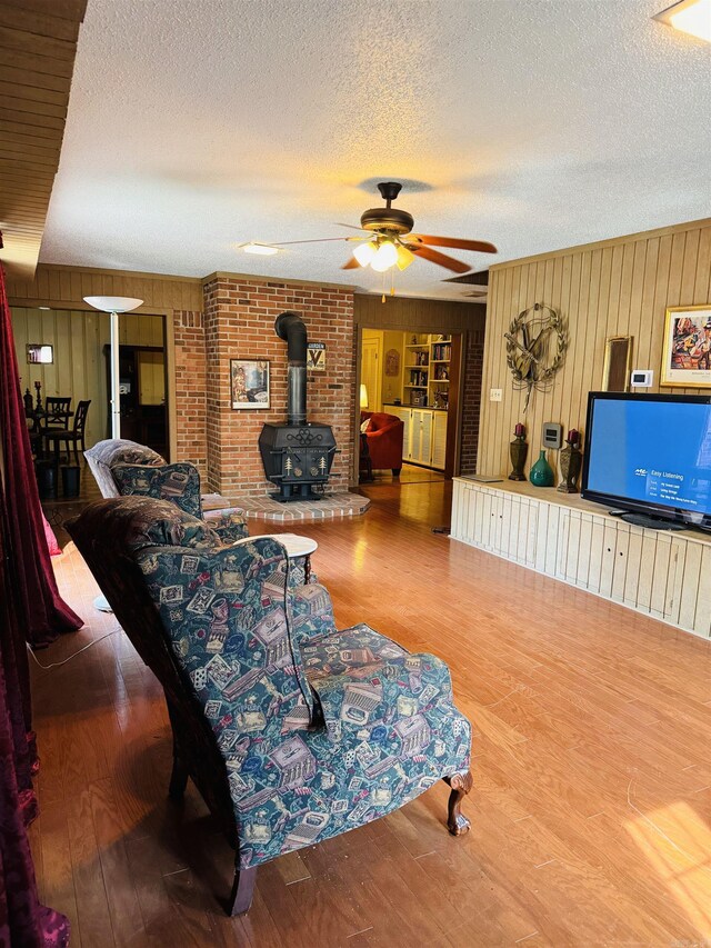 living room featuring hardwood / wood-style floors, a wood stove, a textured ceiling, and wood walls