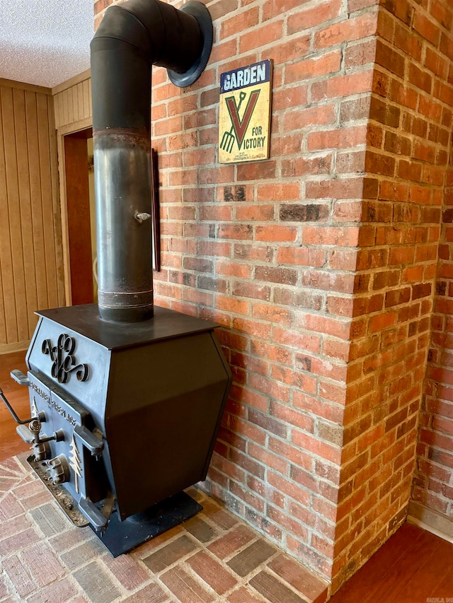 details featuring hardwood / wood-style floors, a wood stove, a textured ceiling, and wood walls