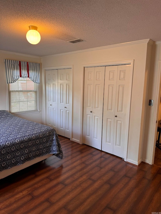 bedroom with a textured ceiling, ornamental molding, and dark hardwood / wood-style flooring