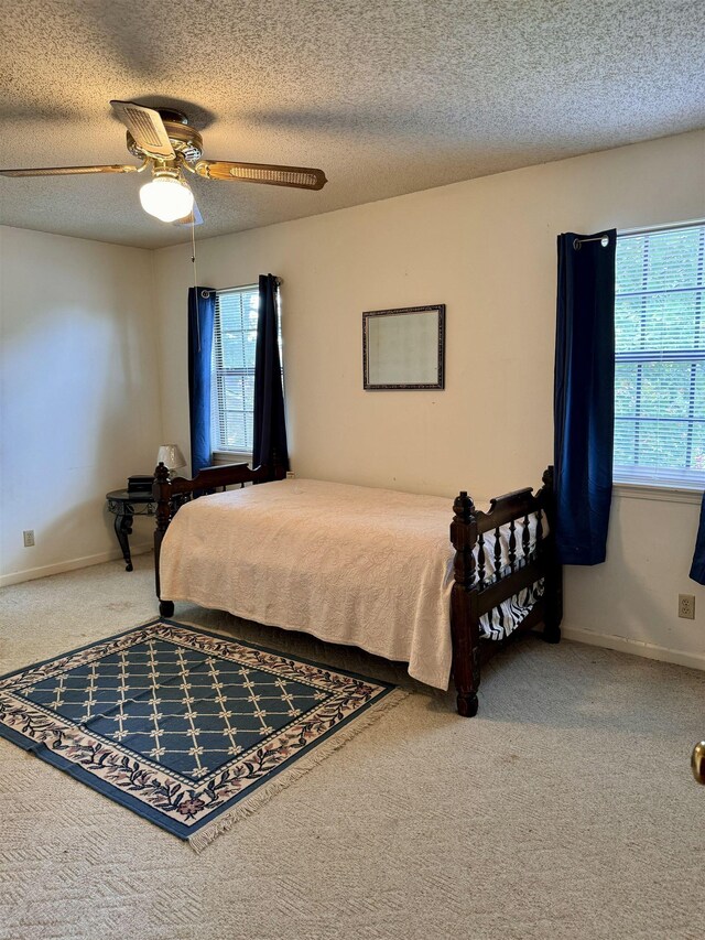 carpeted home office featuring ceiling fan and a textured ceiling