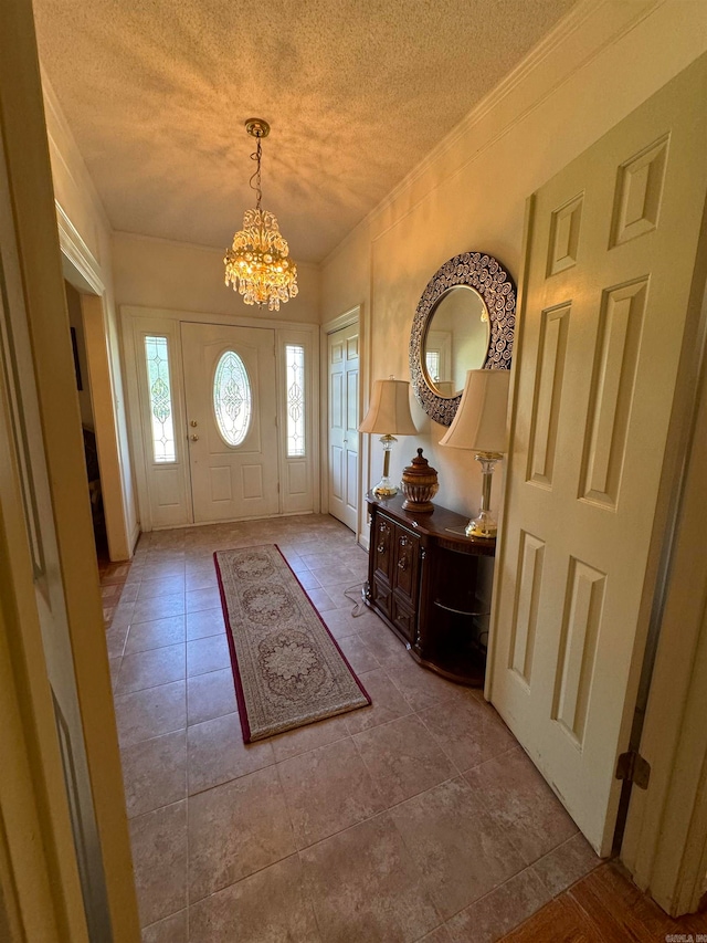 tiled entryway with a textured ceiling and a chandelier