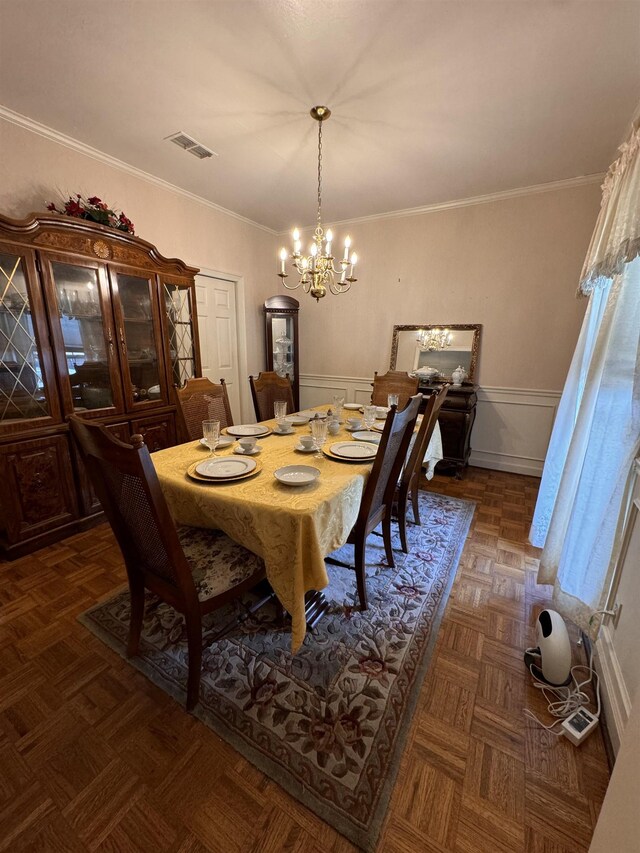 dining space featuring a chandelier, ornamental molding, and dark parquet floors