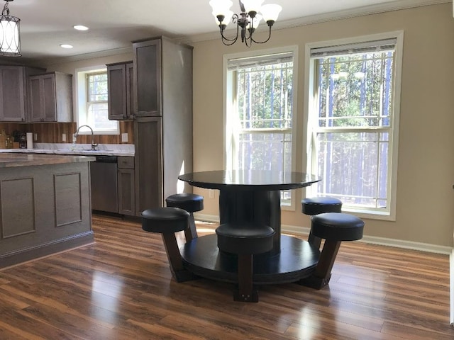 dining area with sink, ornamental molding, a chandelier, and dark hardwood / wood-style floors