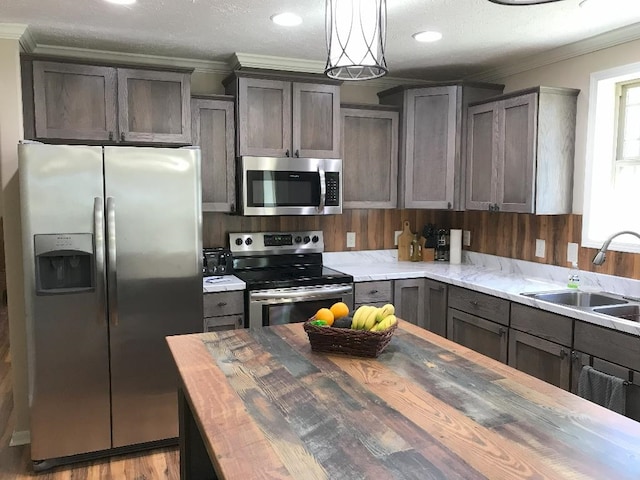 kitchen with wooden counters, stainless steel appliances, ornamental molding, and sink