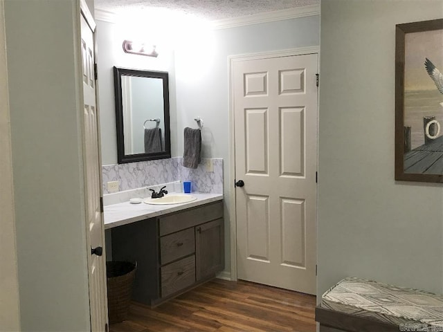 bathroom featuring ornamental molding, tasteful backsplash, wood-type flooring, a textured ceiling, and vanity