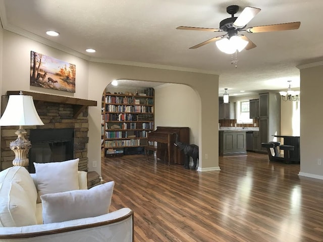 living room featuring a fireplace, dark hardwood / wood-style flooring, sink, ceiling fan, and crown molding