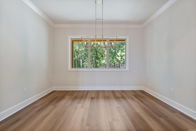 unfurnished room featuring ornamental molding, a chandelier, and wood-type flooring