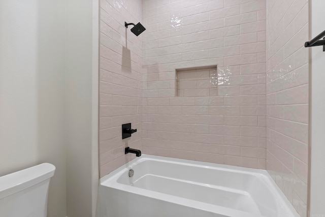 bathroom with toilet and tiled shower / bath