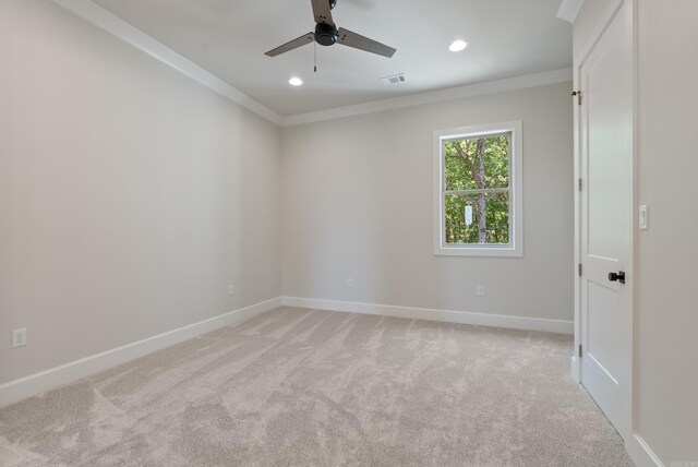 spare room with ceiling fan, ornamental molding, and light carpet