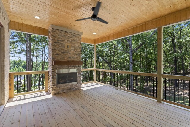 wooden deck featuring ceiling fan and an outdoor stone fireplace