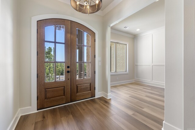 entryway with light wood-type flooring, french doors, and an inviting chandelier