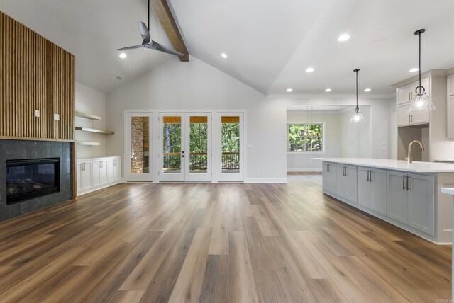 unfurnished living room with light wood-type flooring, high vaulted ceiling, and beam ceiling