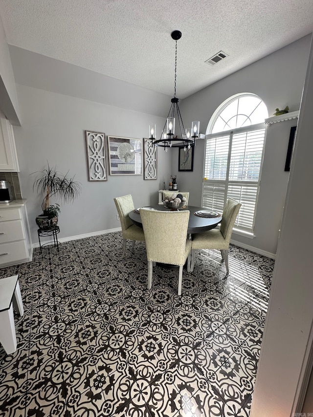 tiled dining space with a notable chandelier and a textured ceiling