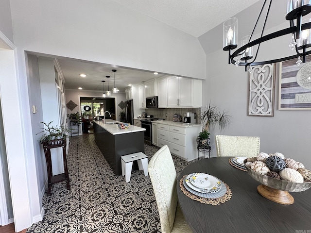 dining space with sink, vaulted ceiling, and an inviting chandelier