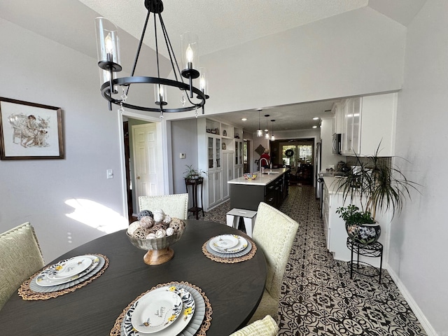 carpeted dining area featuring sink, a textured ceiling, and an inviting chandelier