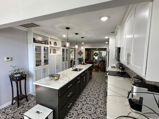 kitchen with sink, light stone countertops, dark tile patterned floors, a kitchen island, and white cabinets