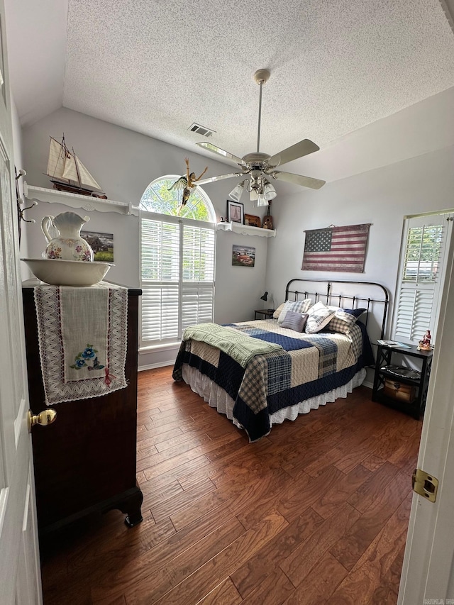 bedroom with hardwood / wood-style flooring, a textured ceiling, lofted ceiling, and ceiling fan