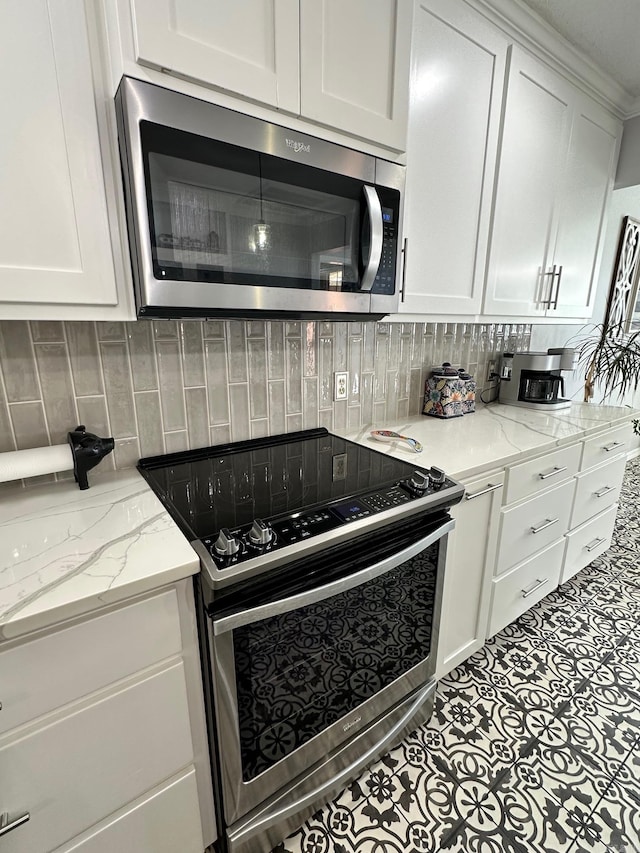 kitchen with appliances with stainless steel finishes, light stone counters, white cabinetry, and backsplash