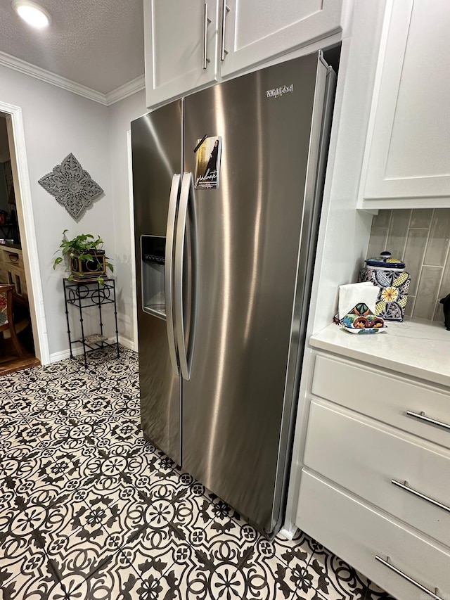 kitchen with light tile patterned flooring, light stone countertops, stainless steel refrigerator with ice dispenser, a textured ceiling, and crown molding