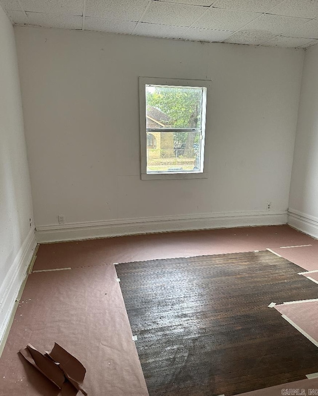 empty room featuring baseboards and a drop ceiling