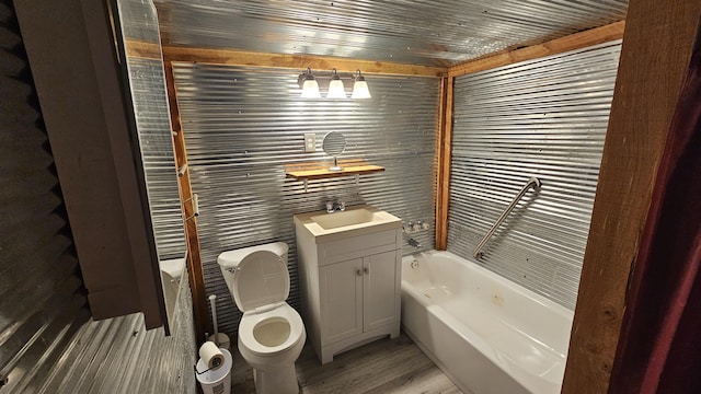 bathroom with a washtub, vanity, toilet, and wood finished floors