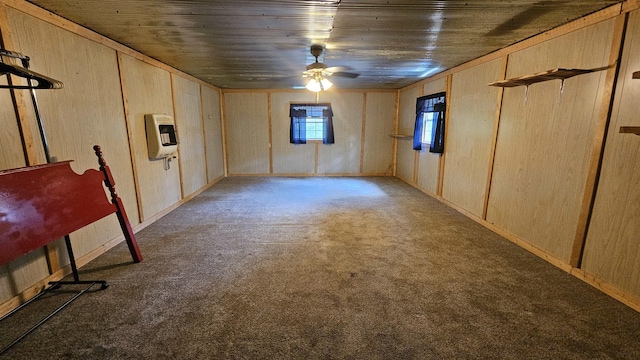 below grade area with carpet floors, heating unit, a ceiling fan, wood ceiling, and wooden walls