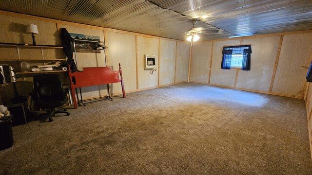 basement with ceiling fan, carpet floors, and wooden walls