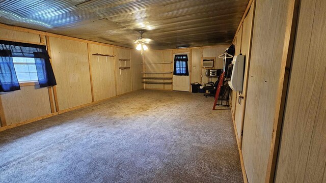 basement with light colored carpet, wooden walls, and ceiling fan