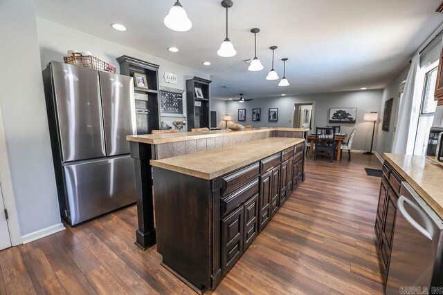 kitchen featuring dark hardwood / wood-style floors, dark brown cabinetry, stainless steel appliances, and hanging light fixtures