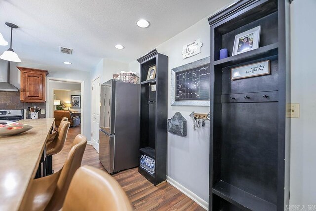 kitchen featuring decorative backsplash, dark hardwood / wood-style floors, pendant lighting, stove, and stainless steel fridge