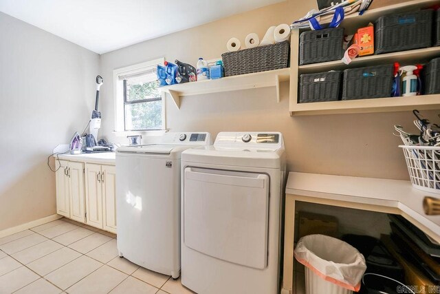 laundry area with light tile patterned floors, cabinets, and washer and dryer