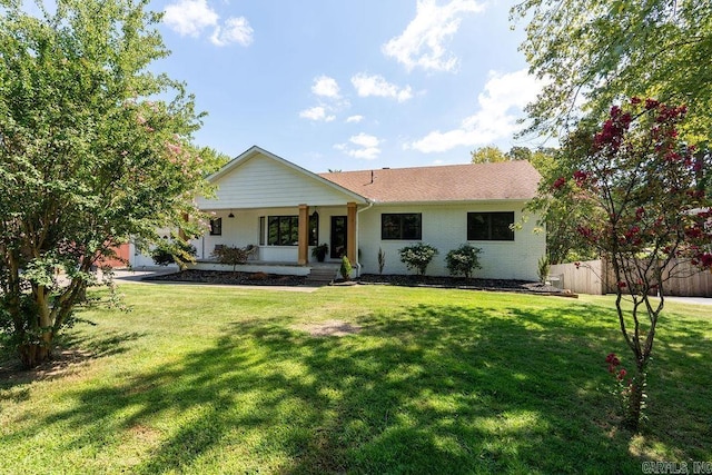 ranch-style house with a front yard, covered porch, brick siding, and fence