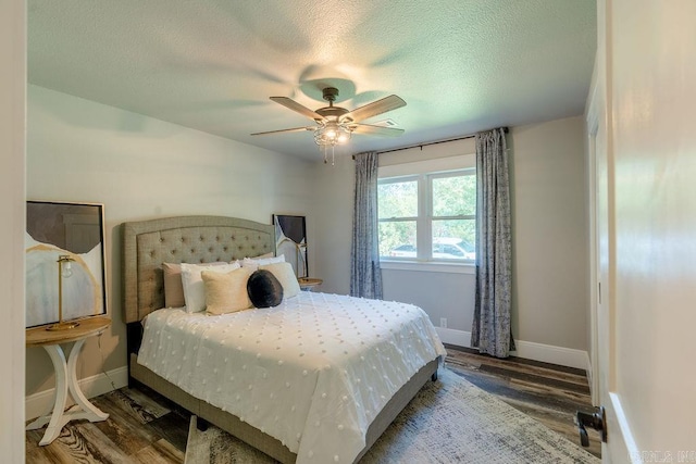 bedroom featuring ceiling fan, a textured ceiling, baseboards, and wood finished floors