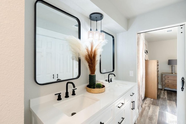 bathroom with double vanity, wood finished floors, a sink, and visible vents