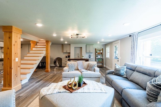 living area featuring light wood finished floors, recessed lighting, a textured ceiling, baseboards, and stairs