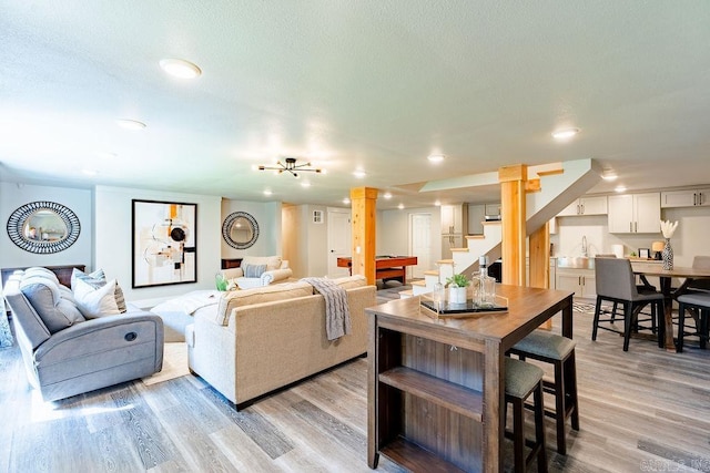 living area featuring light wood-style flooring, stairs, a textured ceiling, and recessed lighting