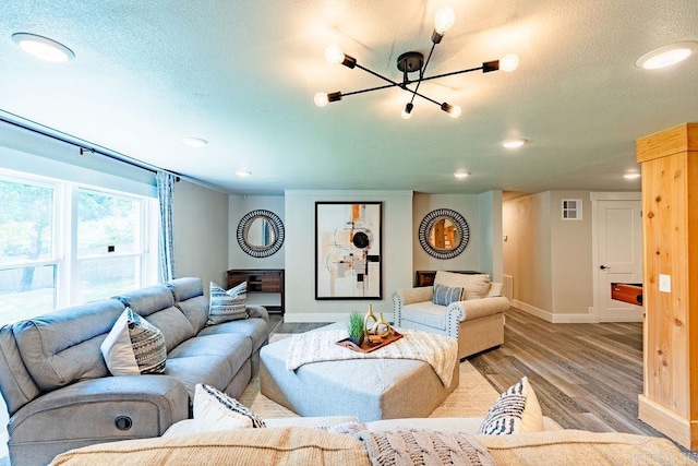 living room featuring a textured ceiling, recessed lighting, visible vents, baseboards, and light wood-type flooring