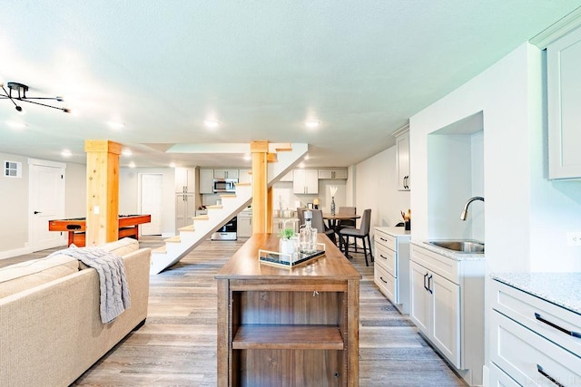 kitchen with white cabinets, stainless steel microwave, light countertops, and a sink